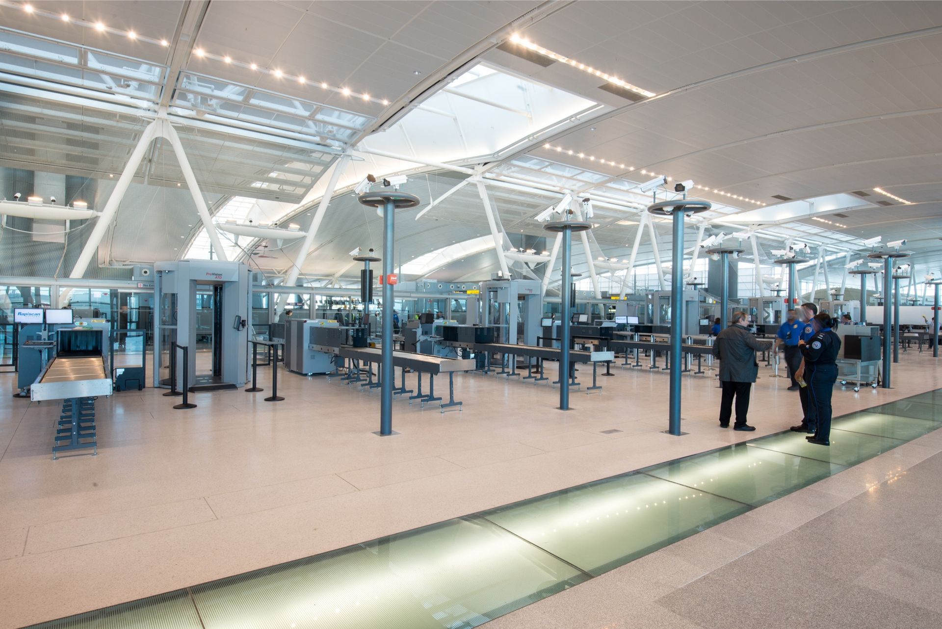 Airport security checkpoint: metal detectors, conveyor belts, people, bright, modern interior.