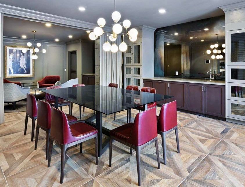 A dining room with a long table and red chairs surrounded by antique mirrors