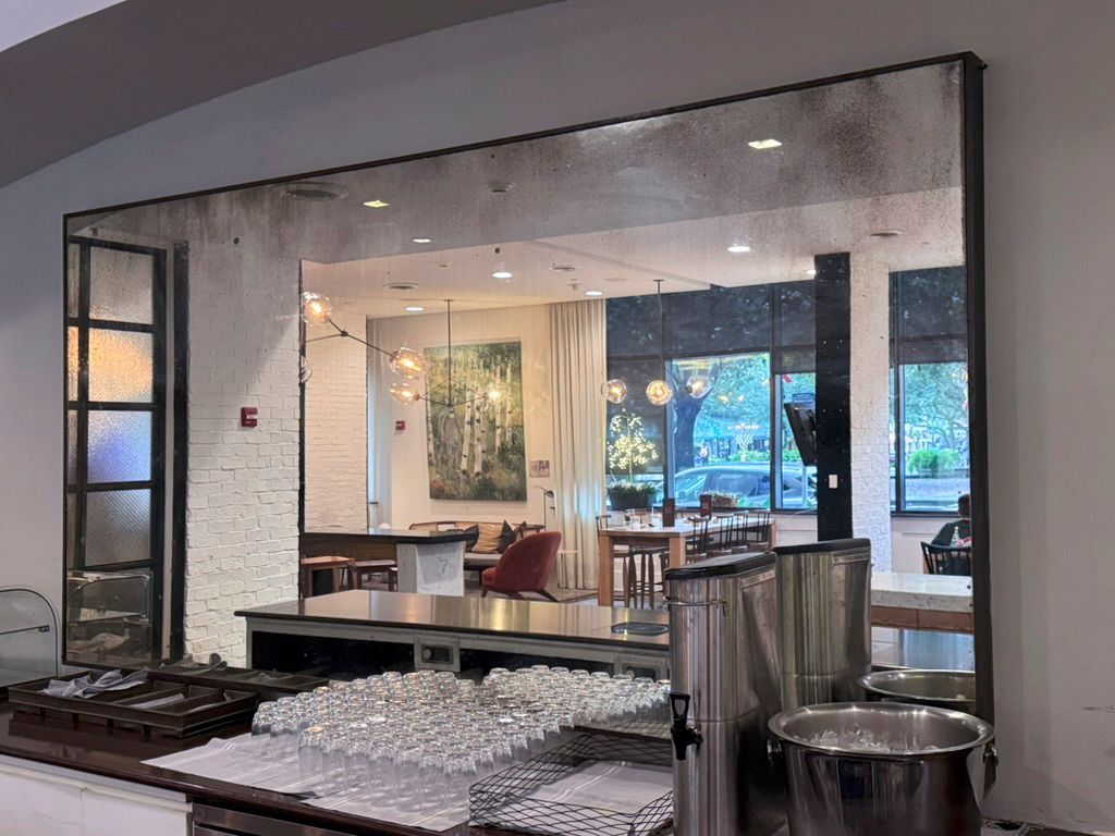 A large mirror is hanging on a wall in a restaurant.
