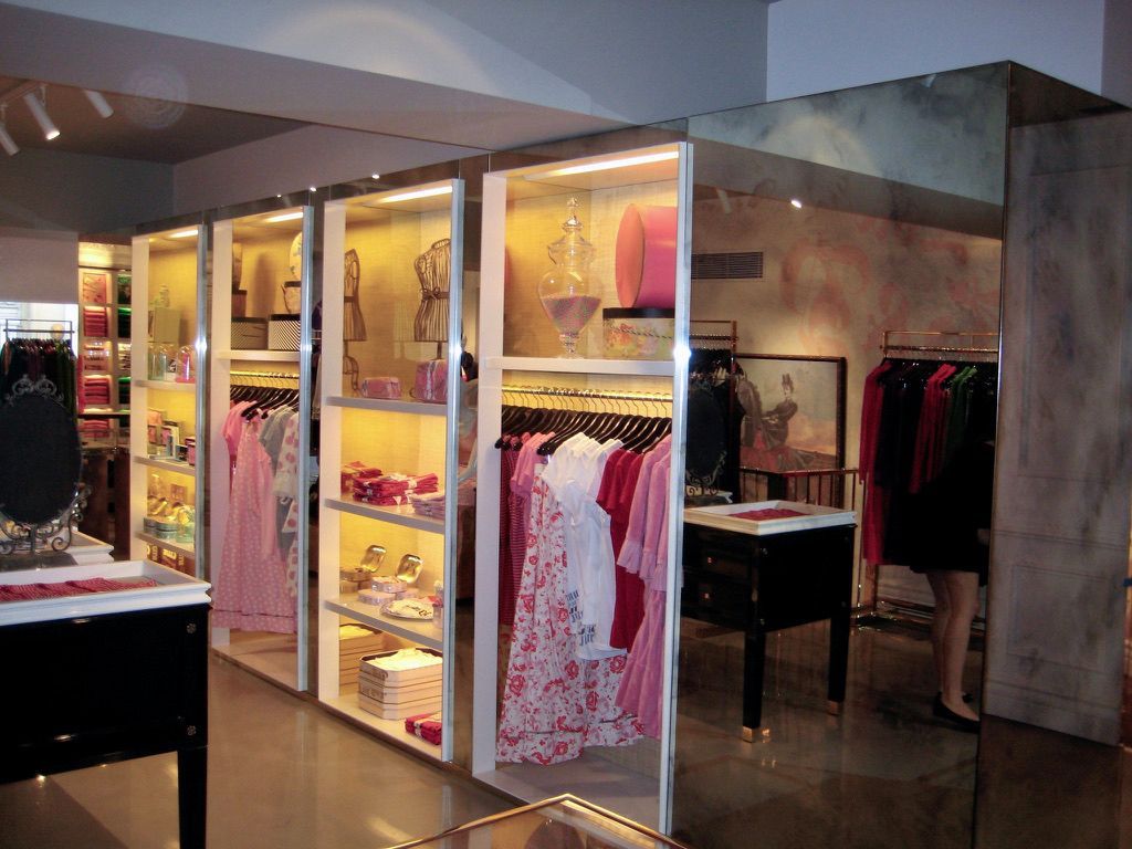 Interior of a retail store with display cases of clothing and accessories. Pink and gold accents.