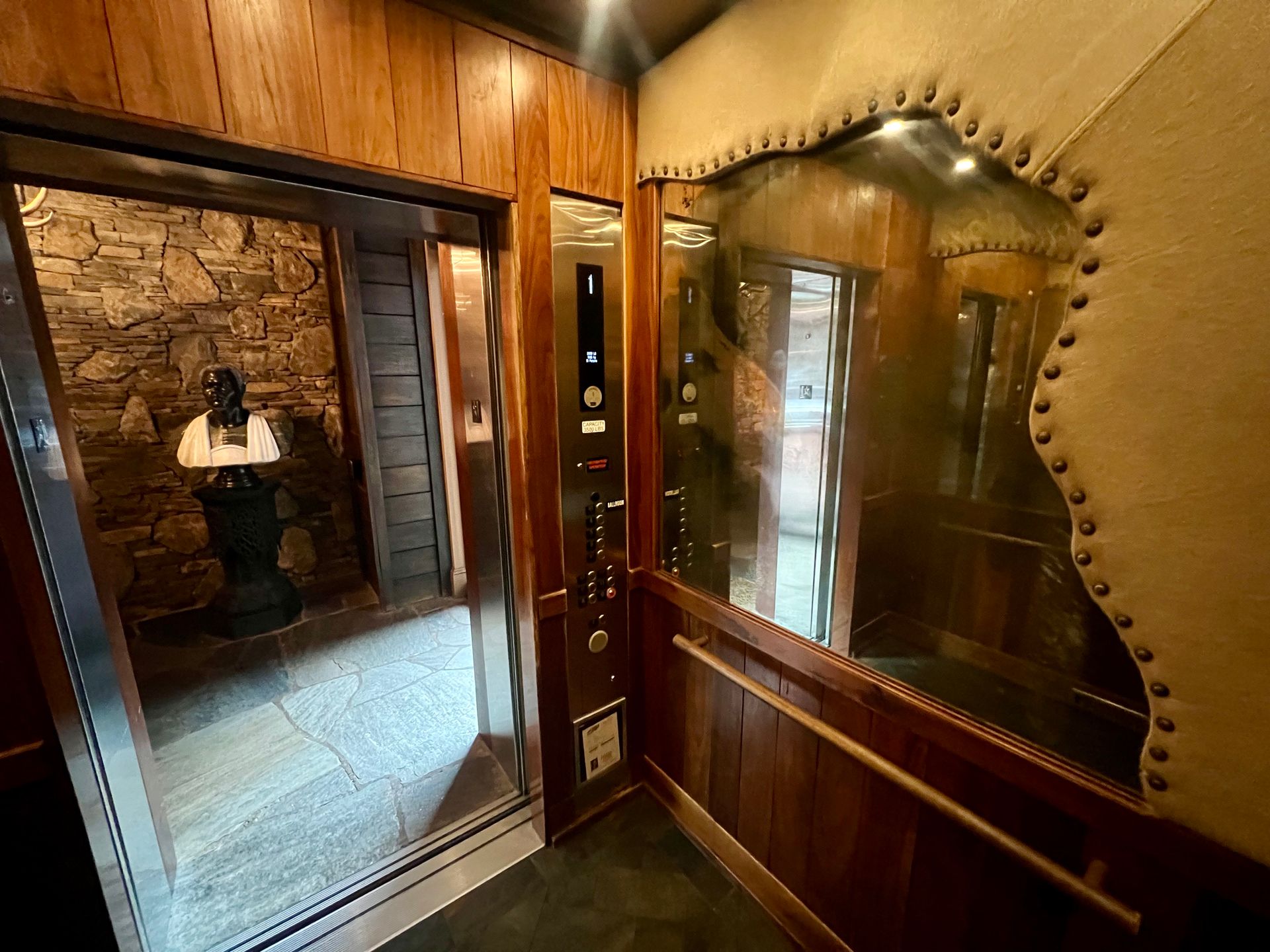 An elevator with a wooden wall and a decorative antique mirror