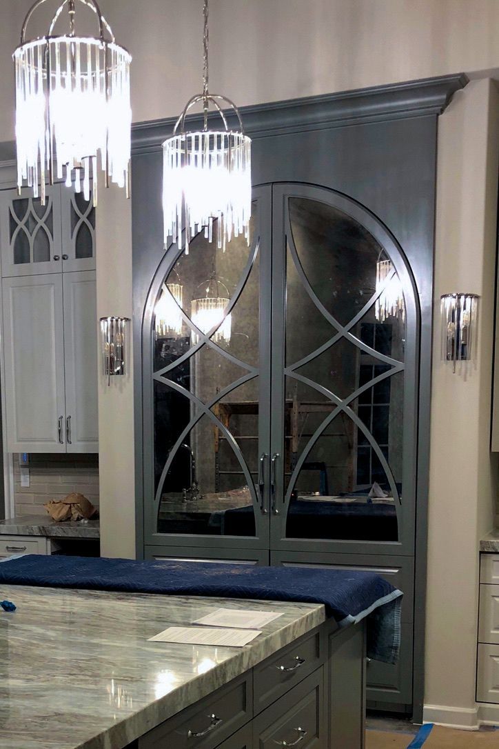 Gray double doors with decorative glass panels, framed by a kitchen island and pendant lights.