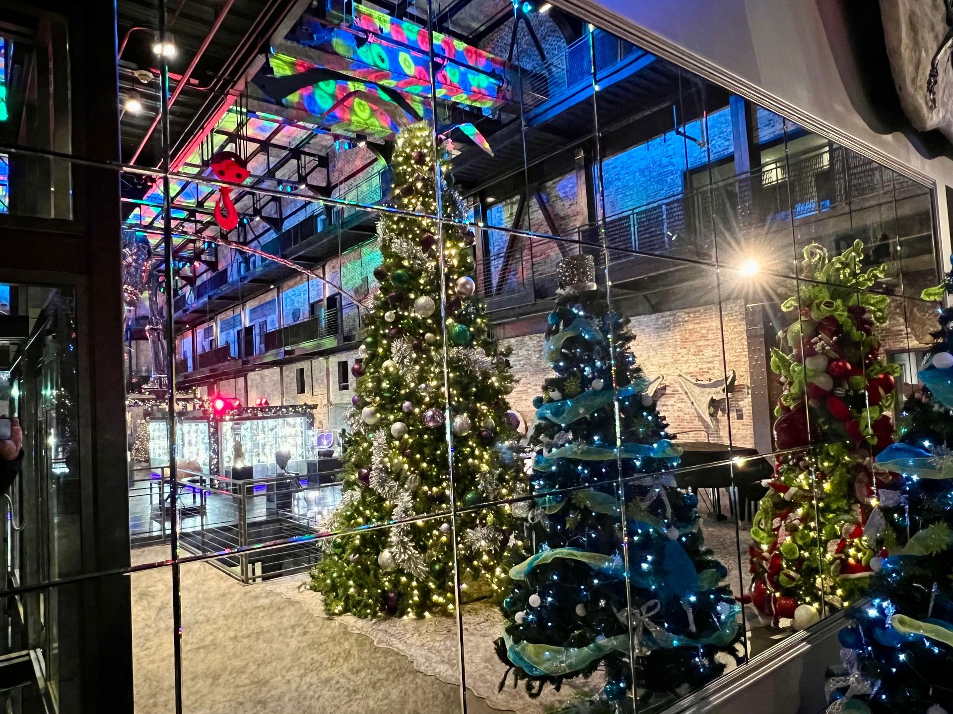 A room filled with lots of christmas trees and decorations with antique mirrors