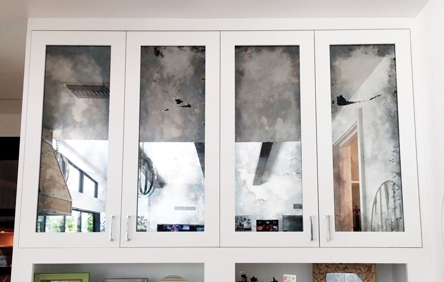 A kitchen with white cabinets and mirrored doors.