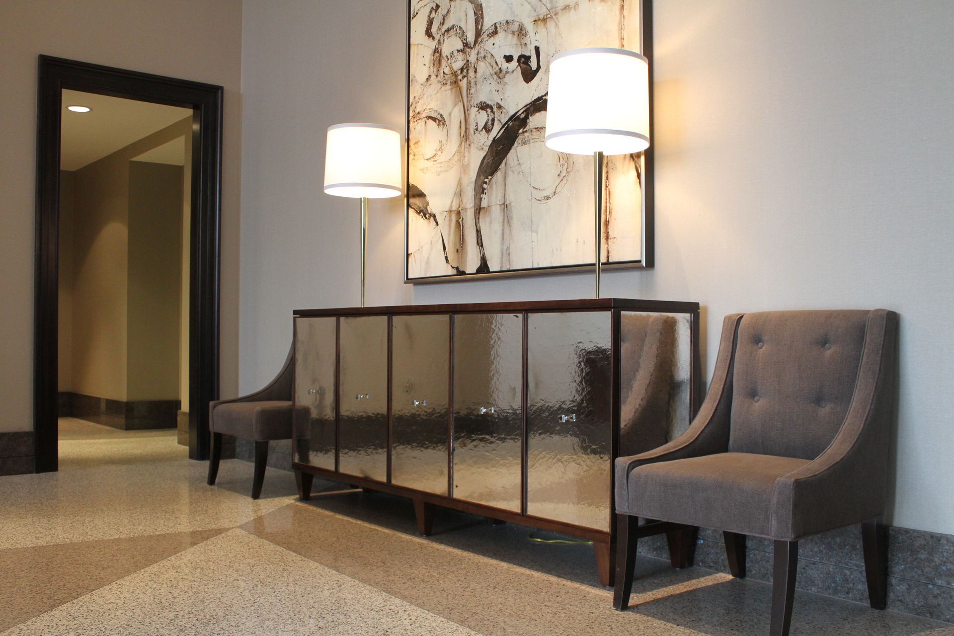 A hallway with chairs and a antique mirrored cabinet