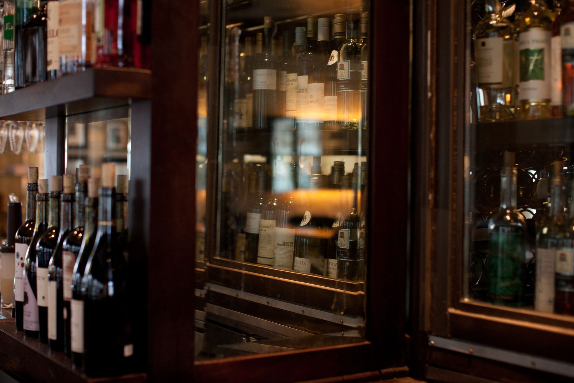A row of wine bottles are lined up on a bar.