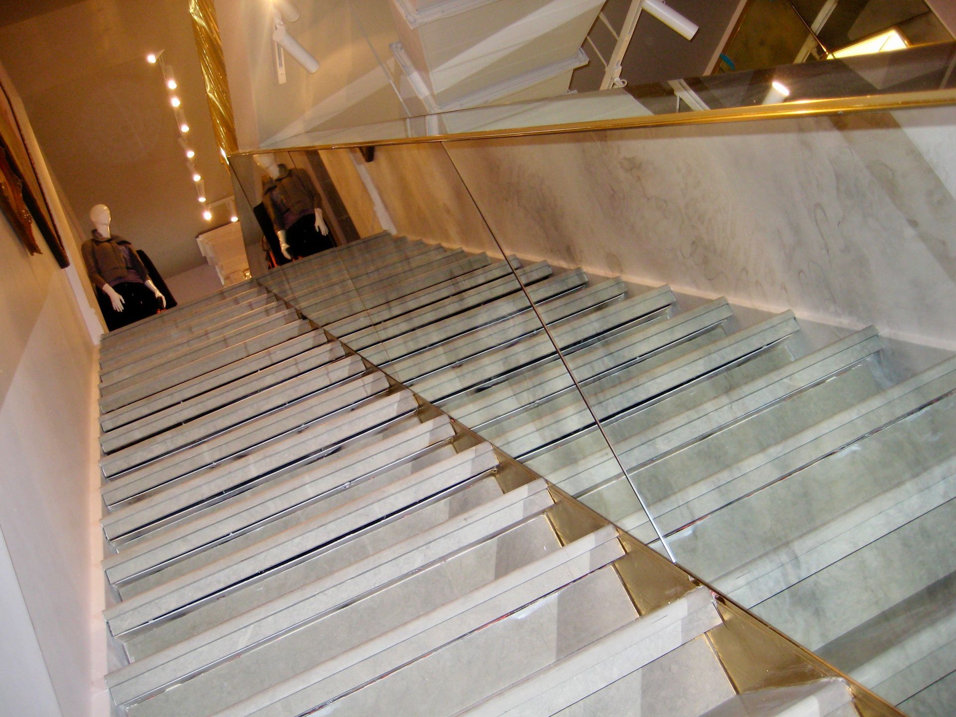 A set of glass stairs with a antique mirrored railing