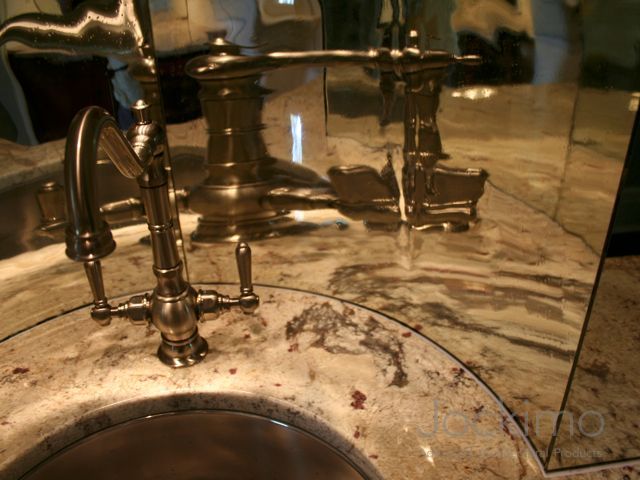 A bathroom sink with an antique mirror behind it