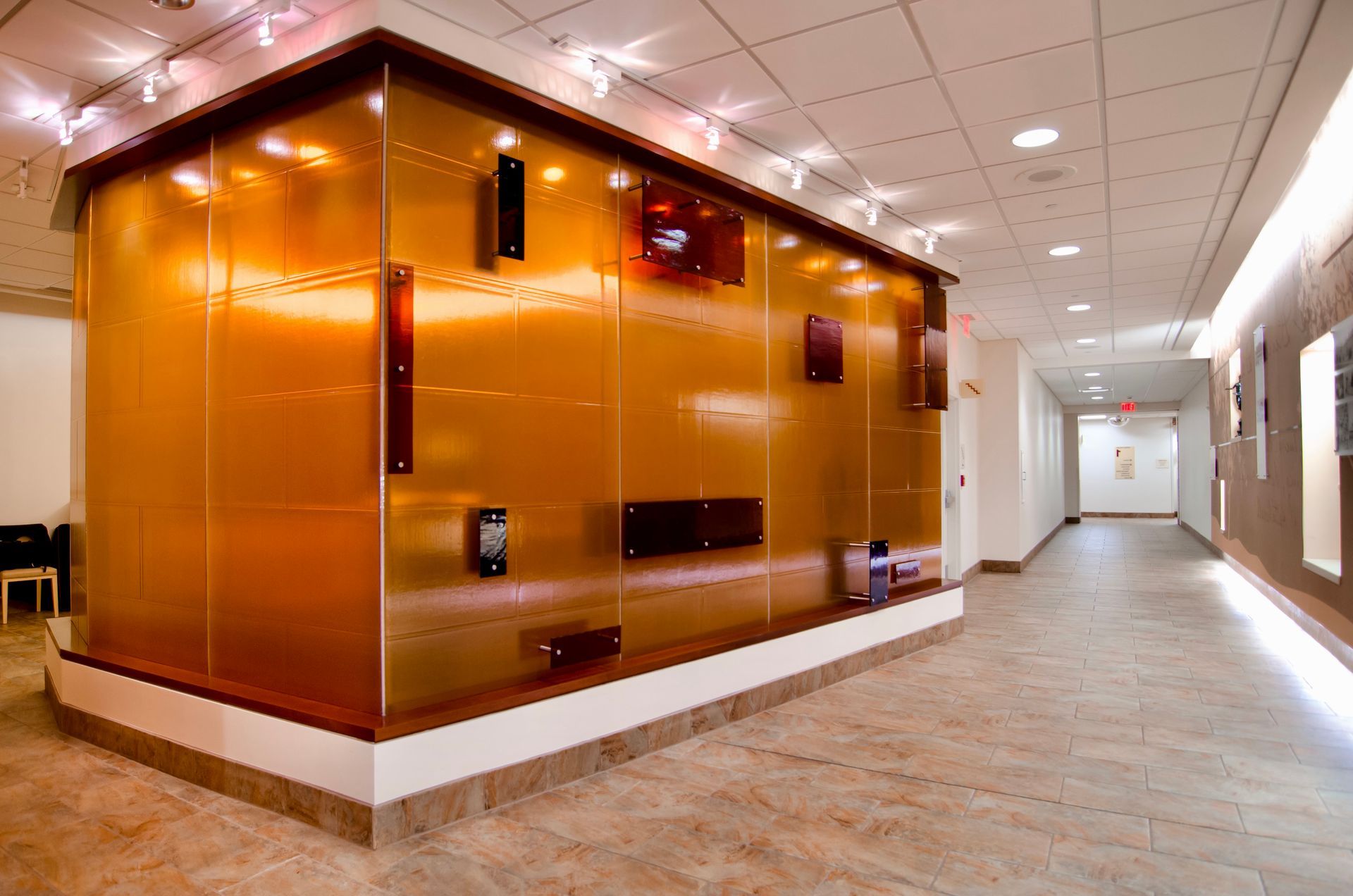 Copper-colored glass structure with rectangular features in a brightly lit hallway.