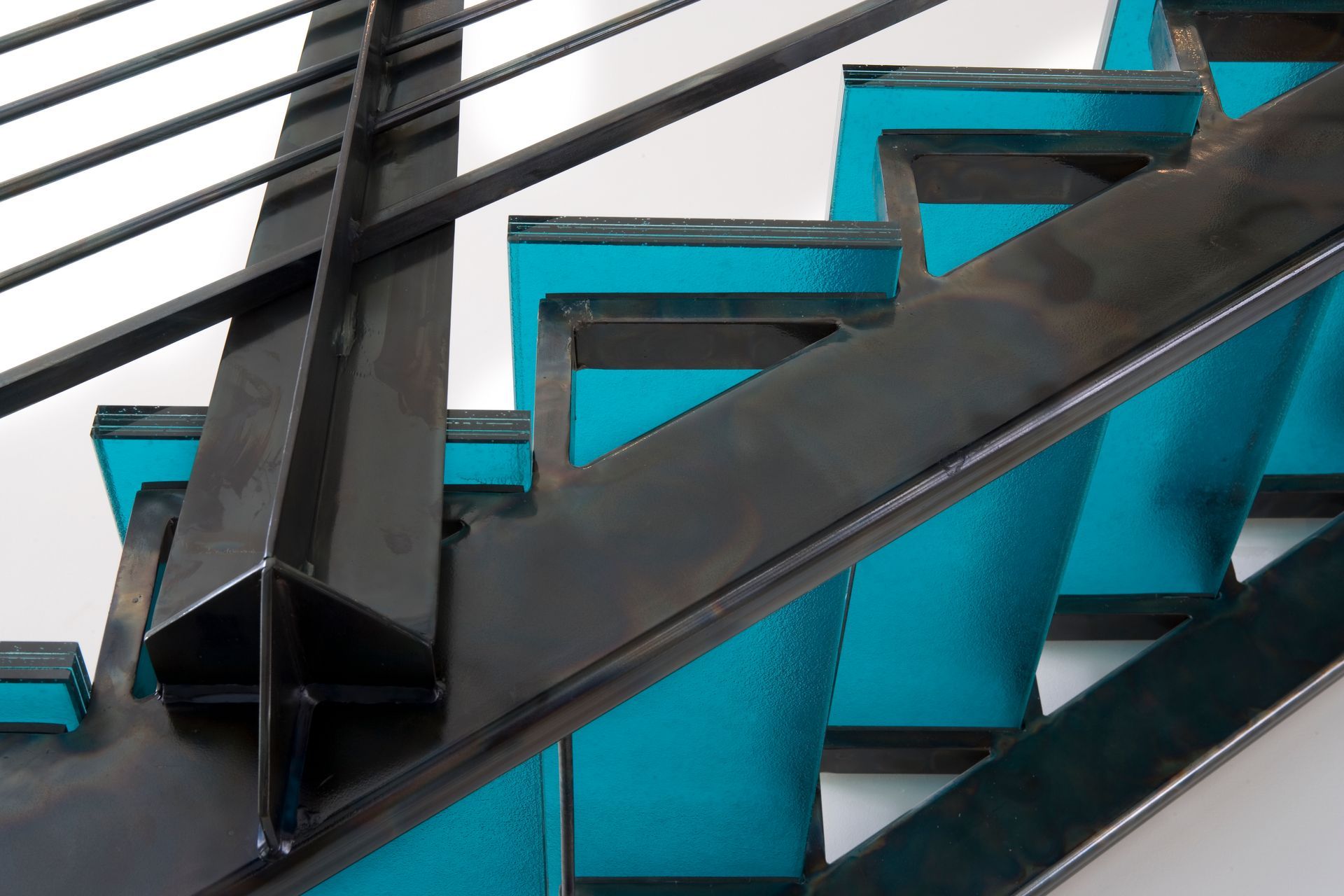 Black metal staircase with turquoise accents and black handrail.
