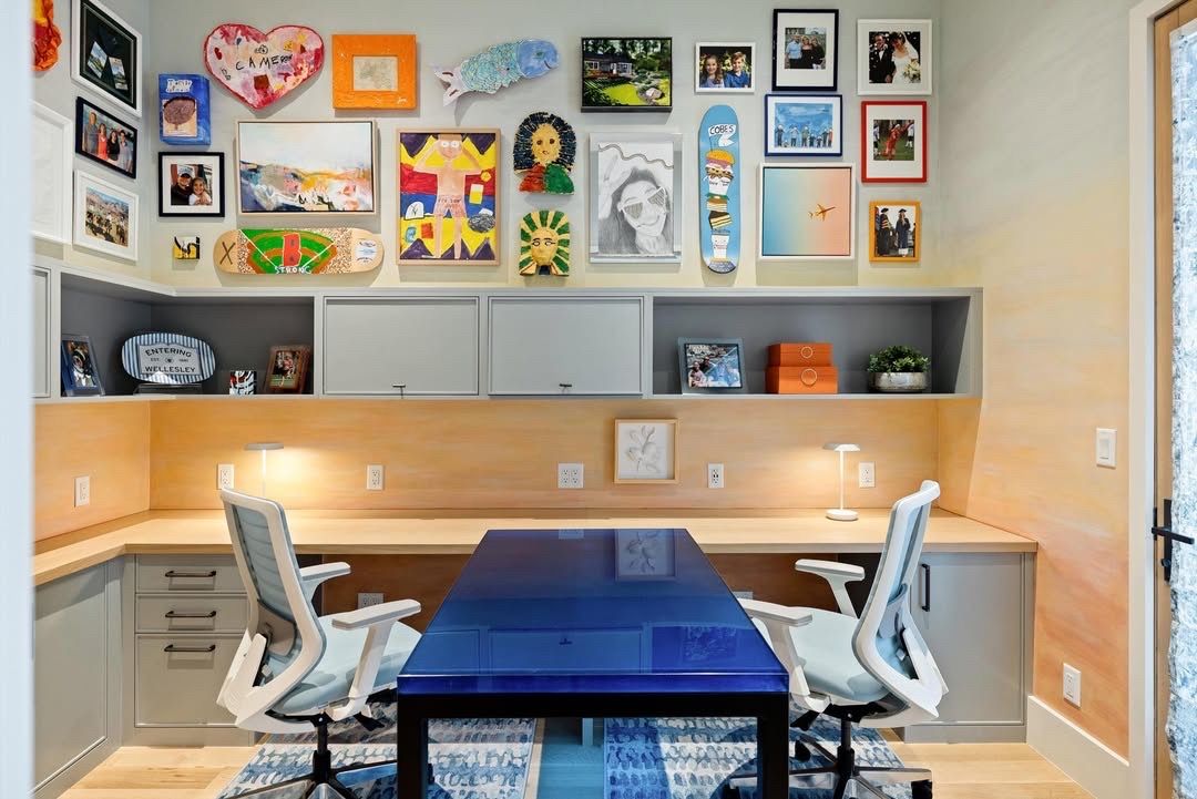 Modern home office with blue table, white chairs, built-in desk, and colorful wall art