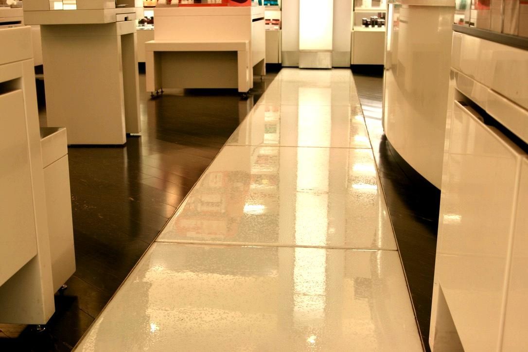 Shiny white and black tile floor in a well-lit retail store with displays and merchandise.