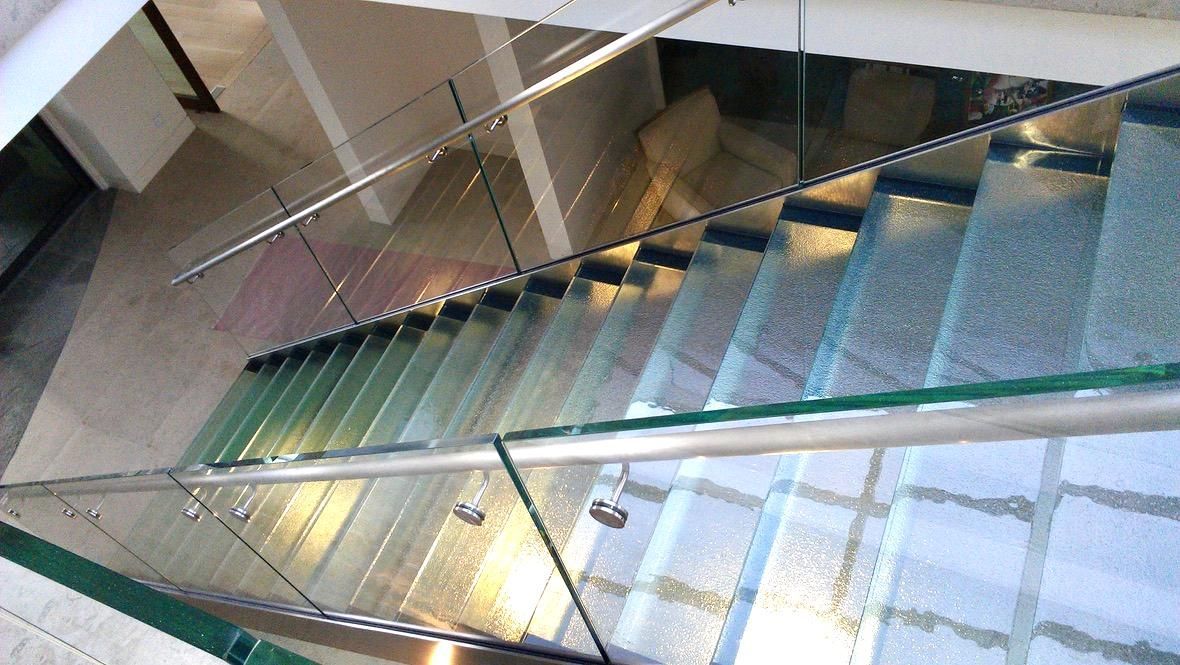 Glass staircase with metal handrails and glass sides.