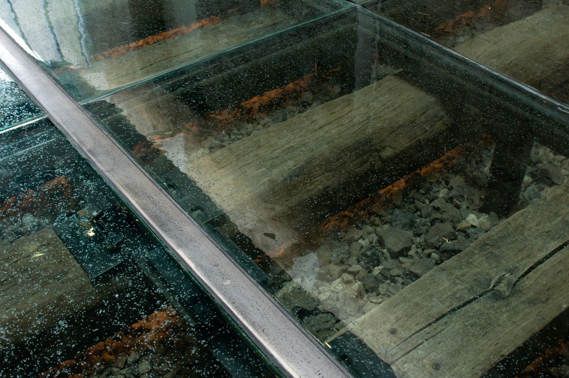 Glass floor view of old wooden railway tracks.