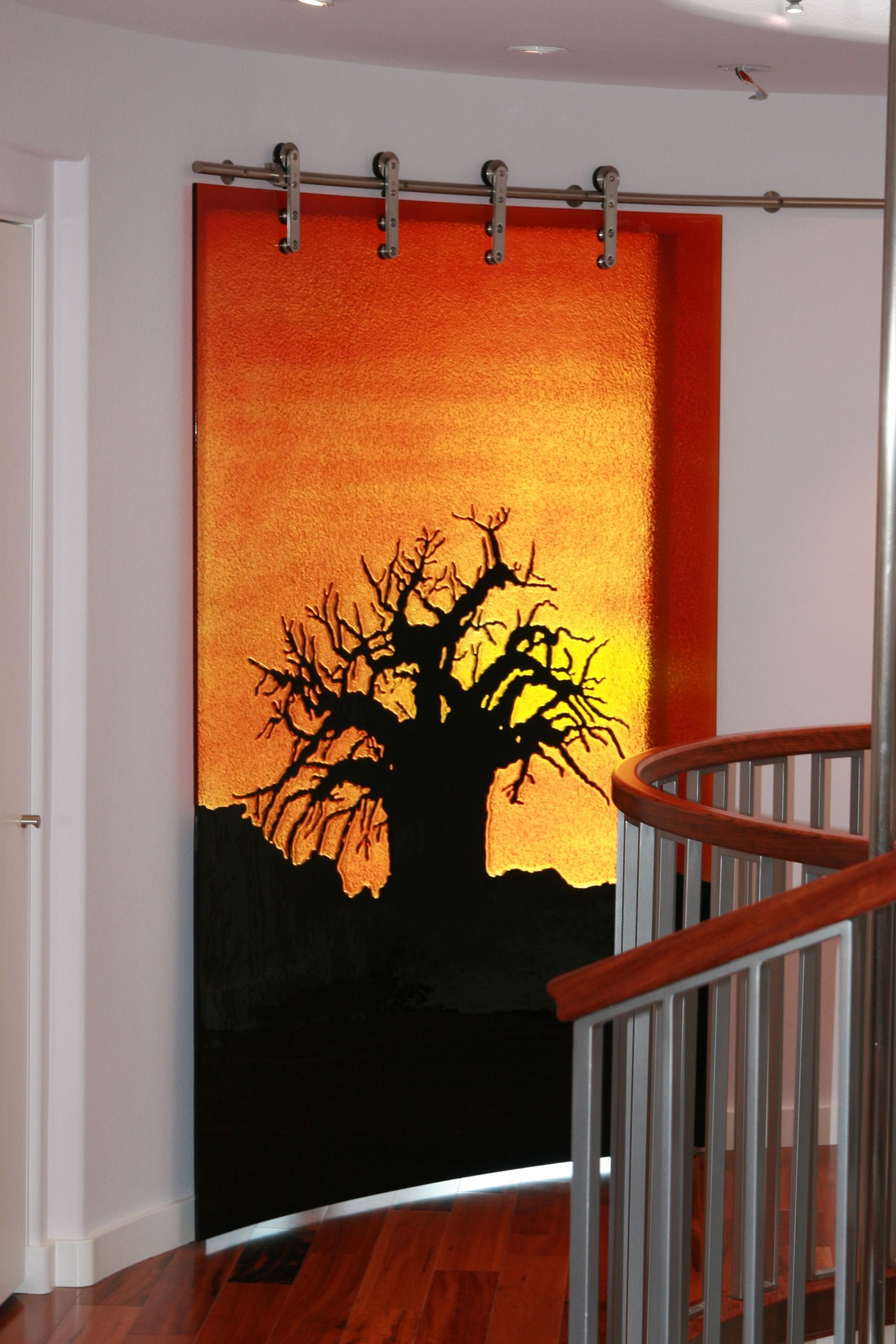 A glass door with the image of a sunset and a tree in silhouette.