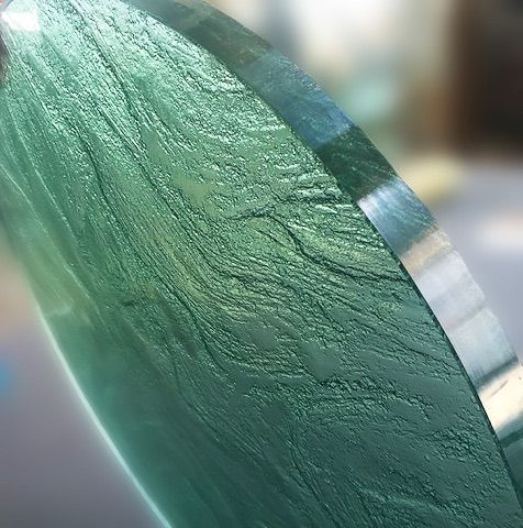 A close up of thick green glass circle on a table
