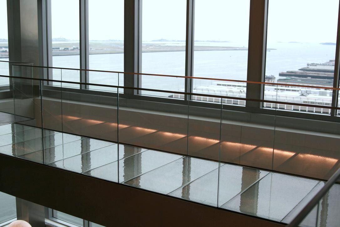 Interior shot with glass floor and large windows overlooking water.