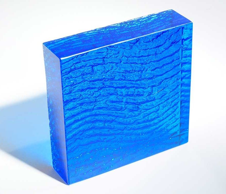 A square of thick blue glass with an integrated wave pattern.