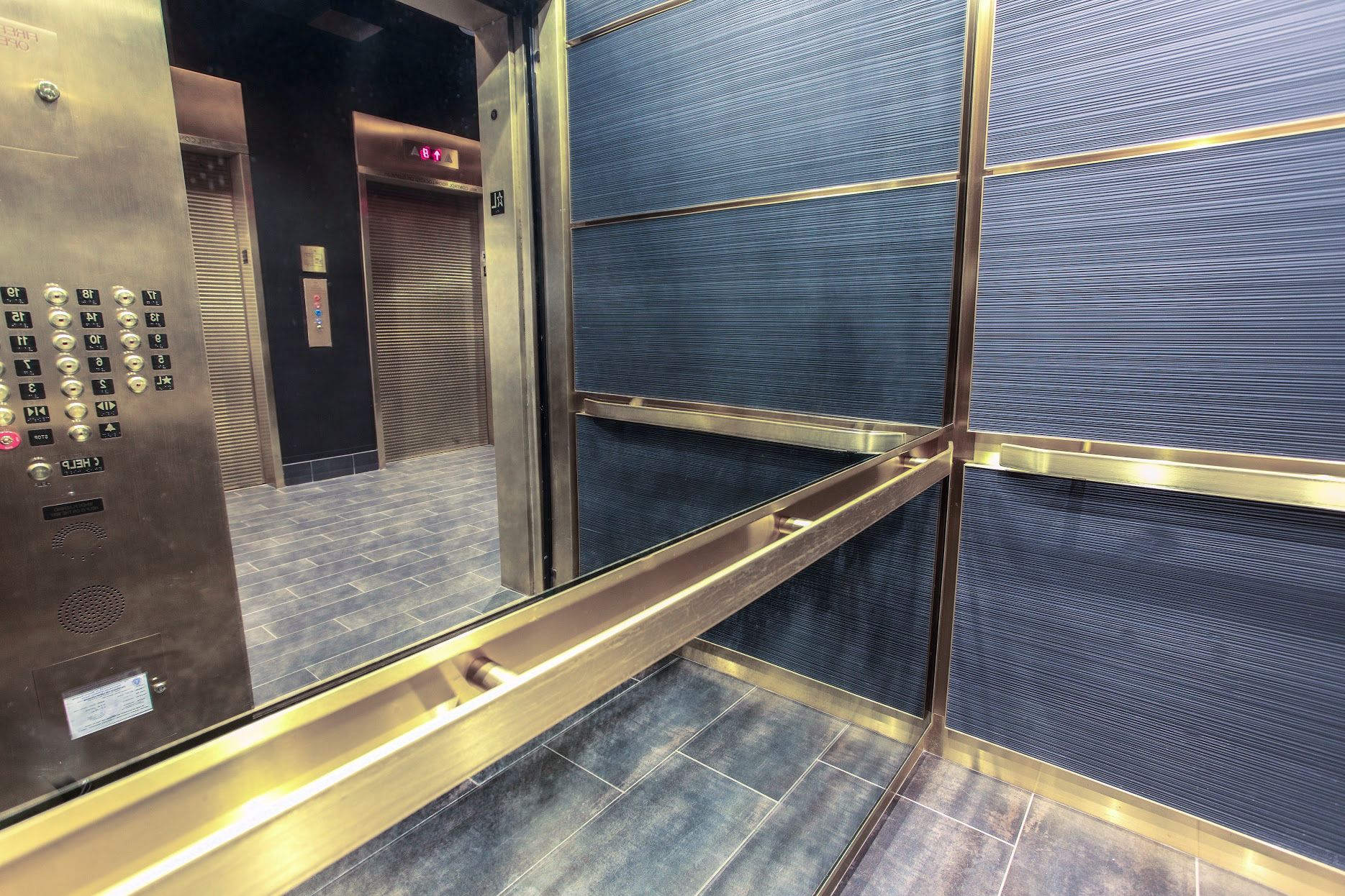 The inside of an elevator with buttons and a antique mirrors