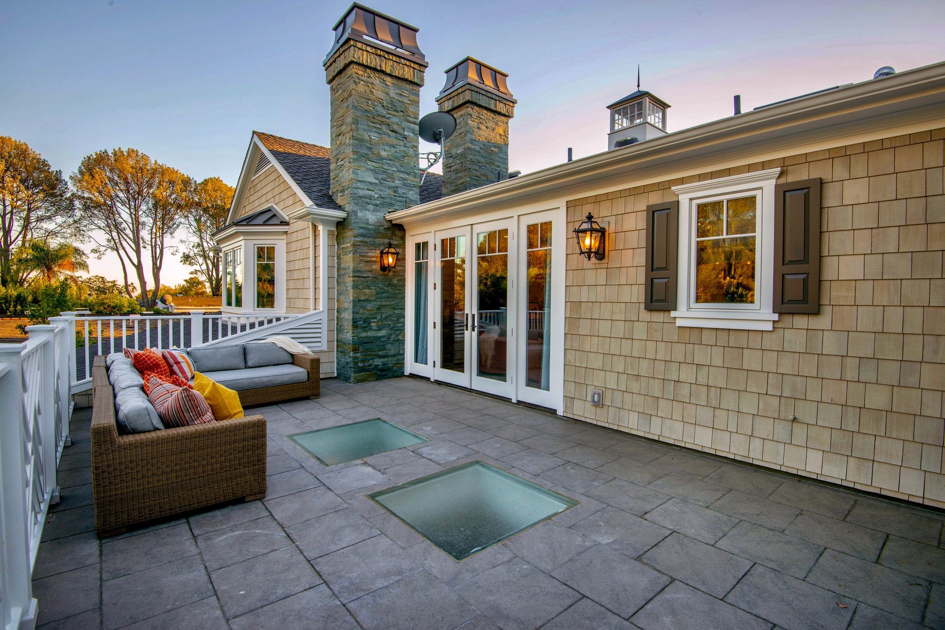Patio with wicker sofa, glass floor panels, double doors, stone chimney, and glass flooring panels