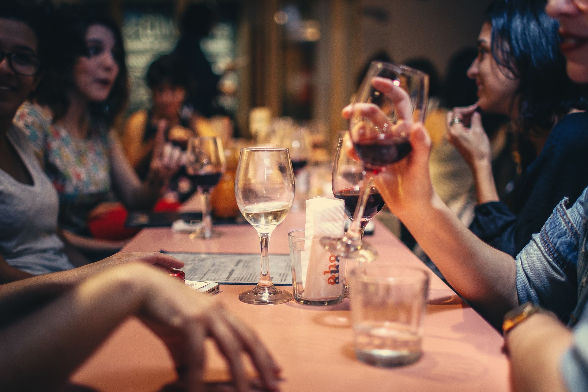 Friends talking and laughing at a restaurant over wine.