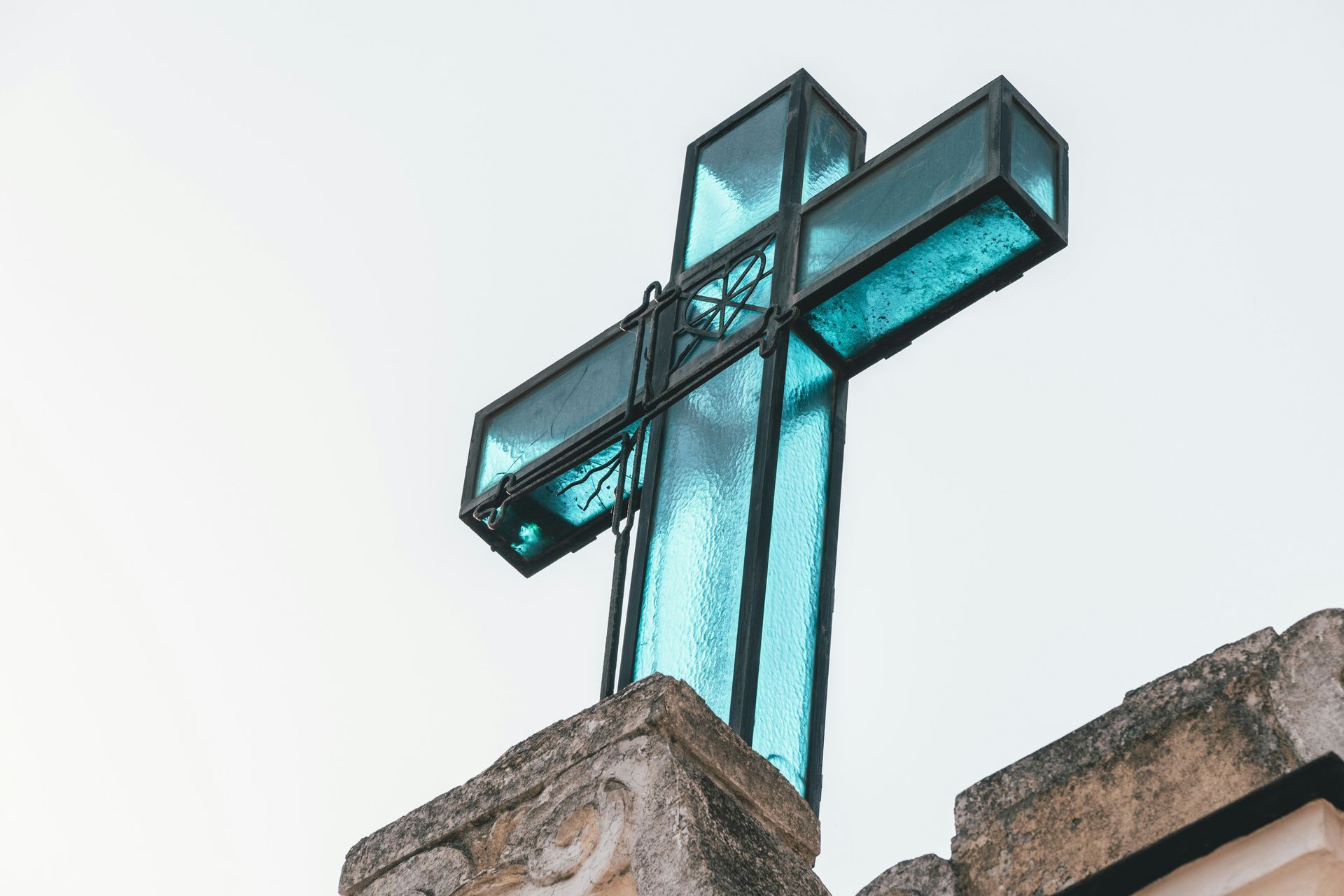 A glass cross with a black metal outline shot from below.