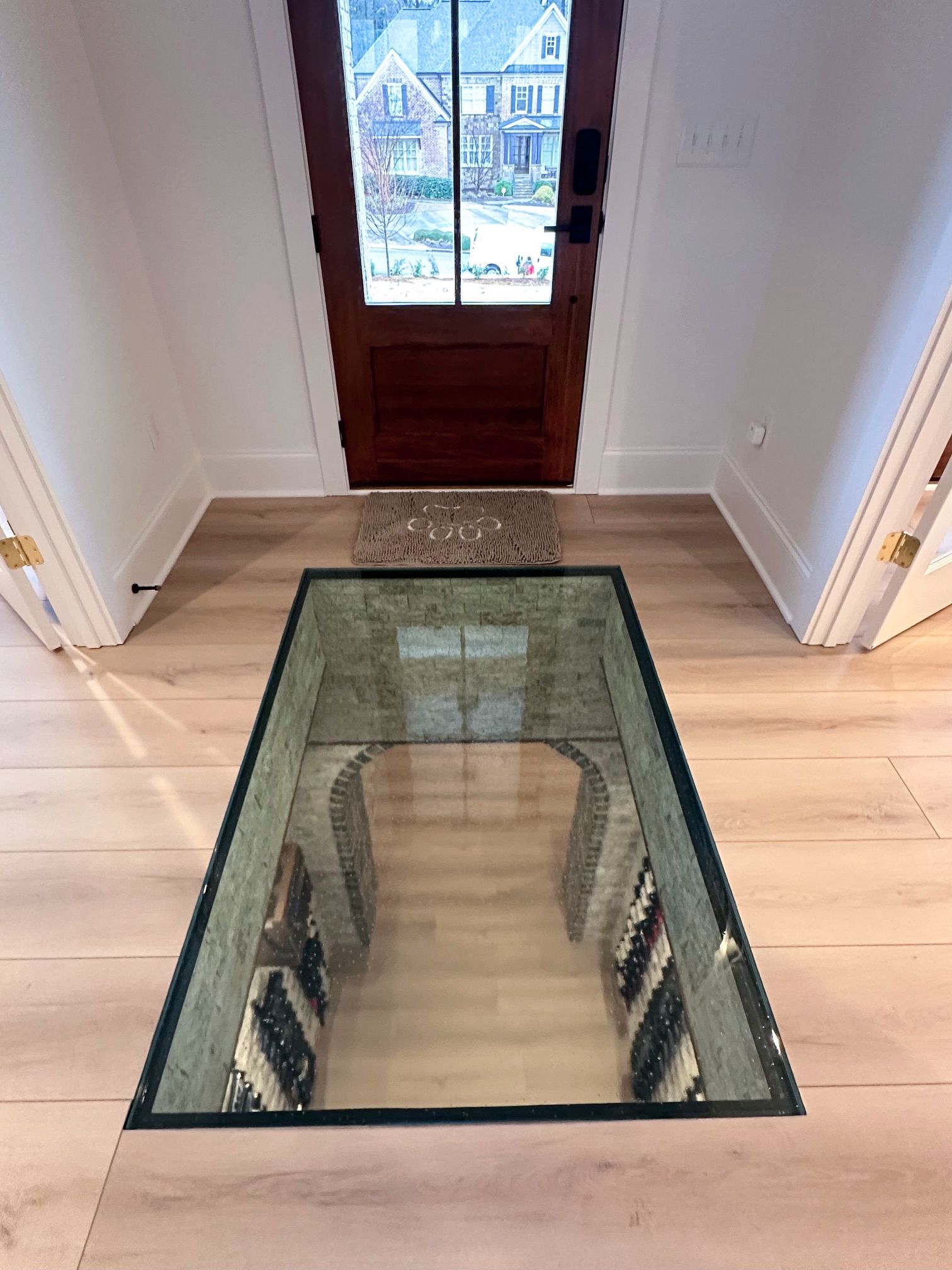 A custom glass floor installed in an upscale home revealing an intricate stone wine cellar below.