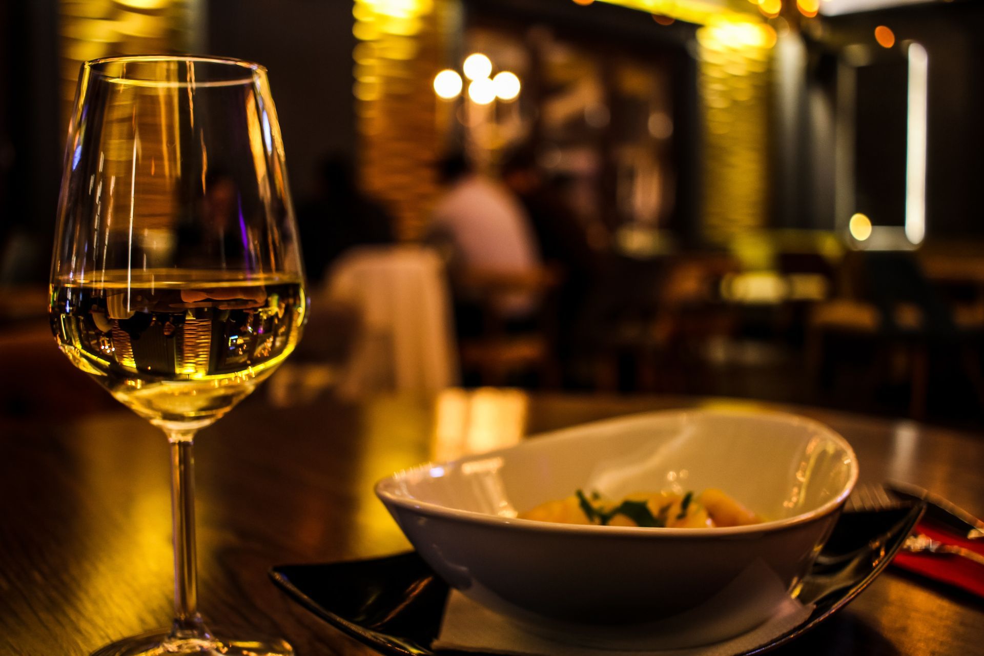 A glass of wine and a dish of food at an upscale restaurant.