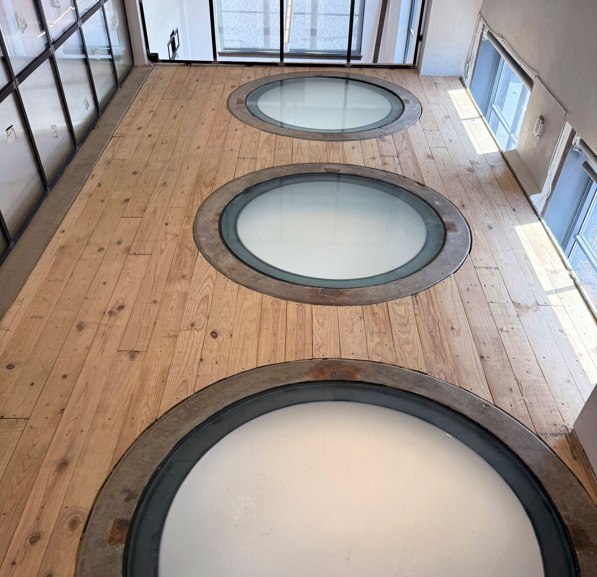 Wooden floor with three circular windows looking up to the ceiling.