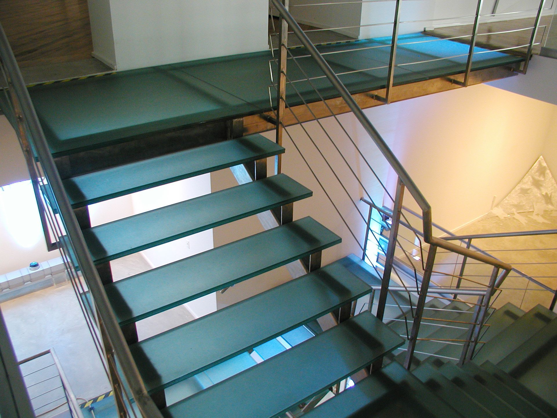 Modern steel staircase with glass steps in a building.