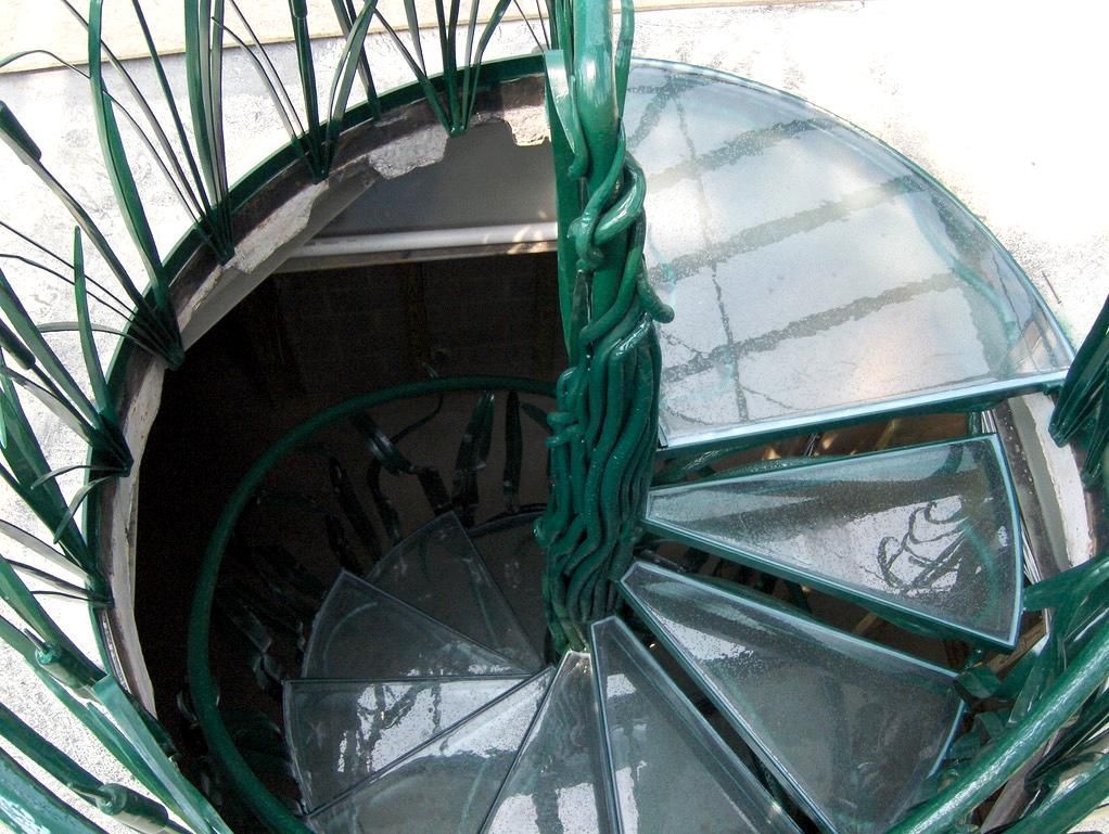 A spiral staircase with a green railing and a glass top