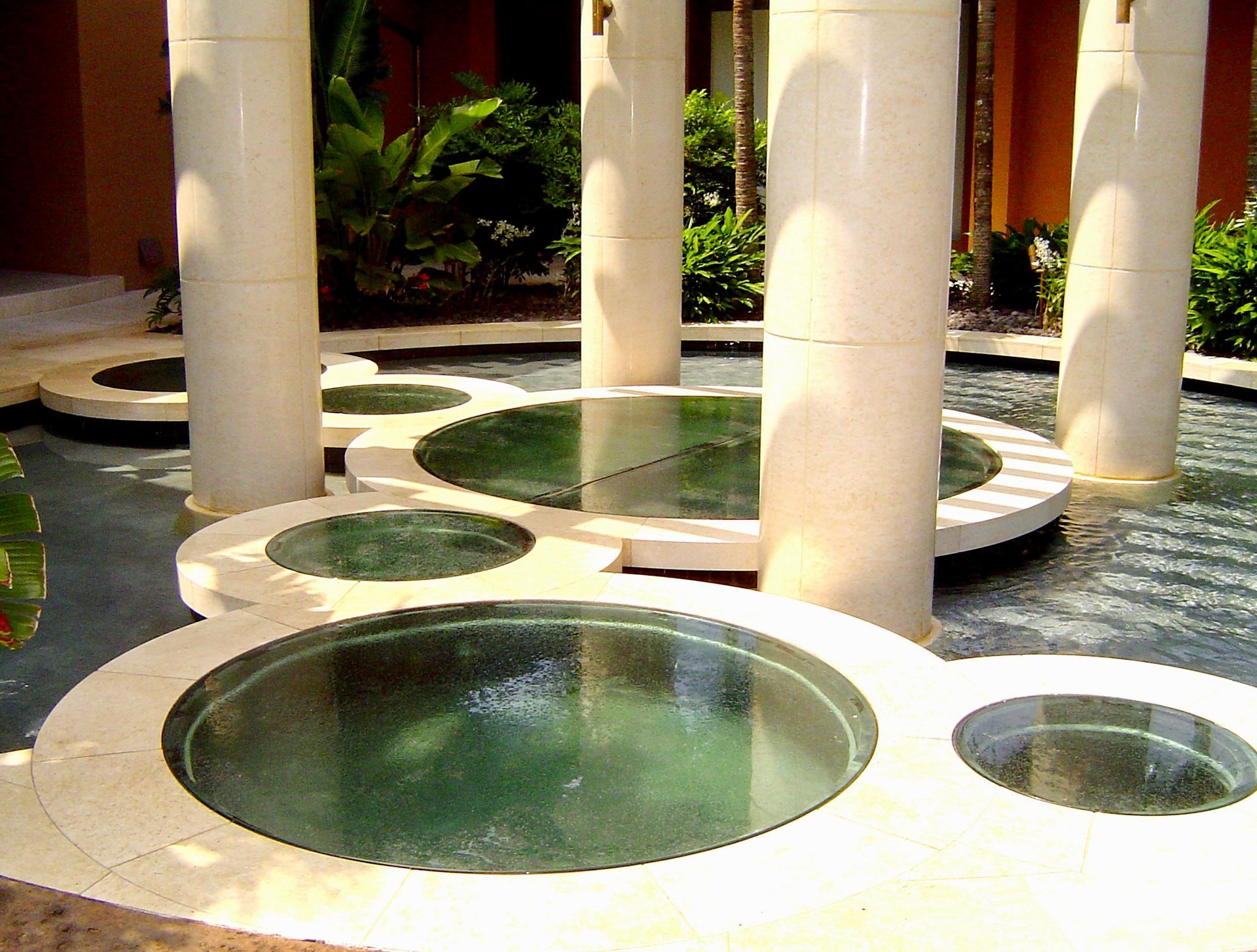 A shallow water feature with tiered, circular stone platforms surrounding several tall white columns.