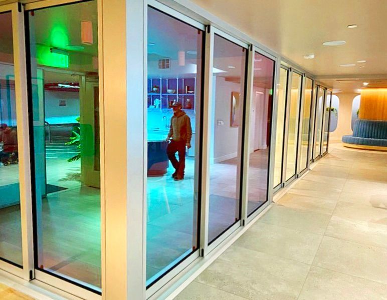 A man is walking through a hallway with a lot of dichroic glass mirrors