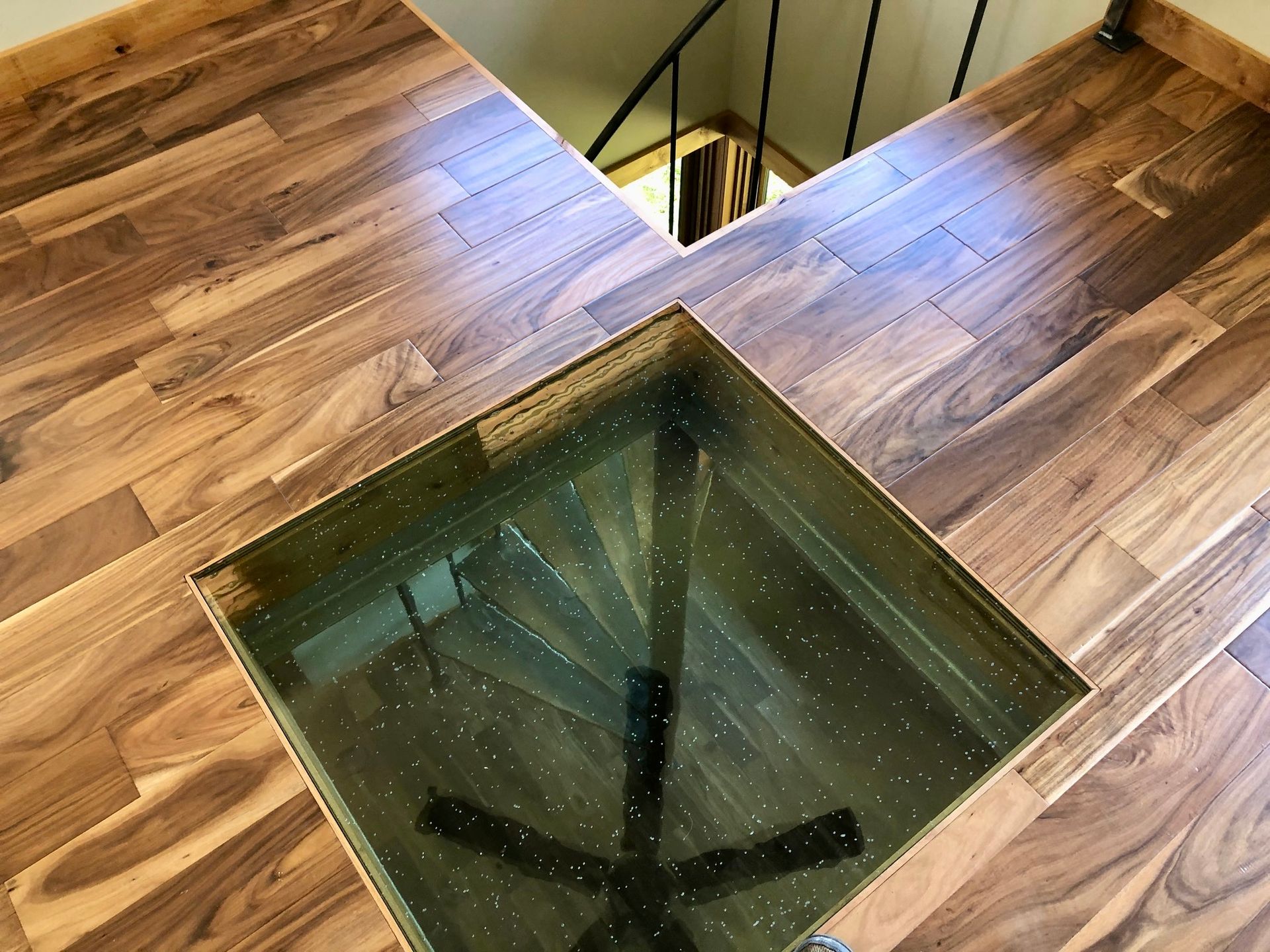 Wooden floor with a glass floor square revealing stairs below.