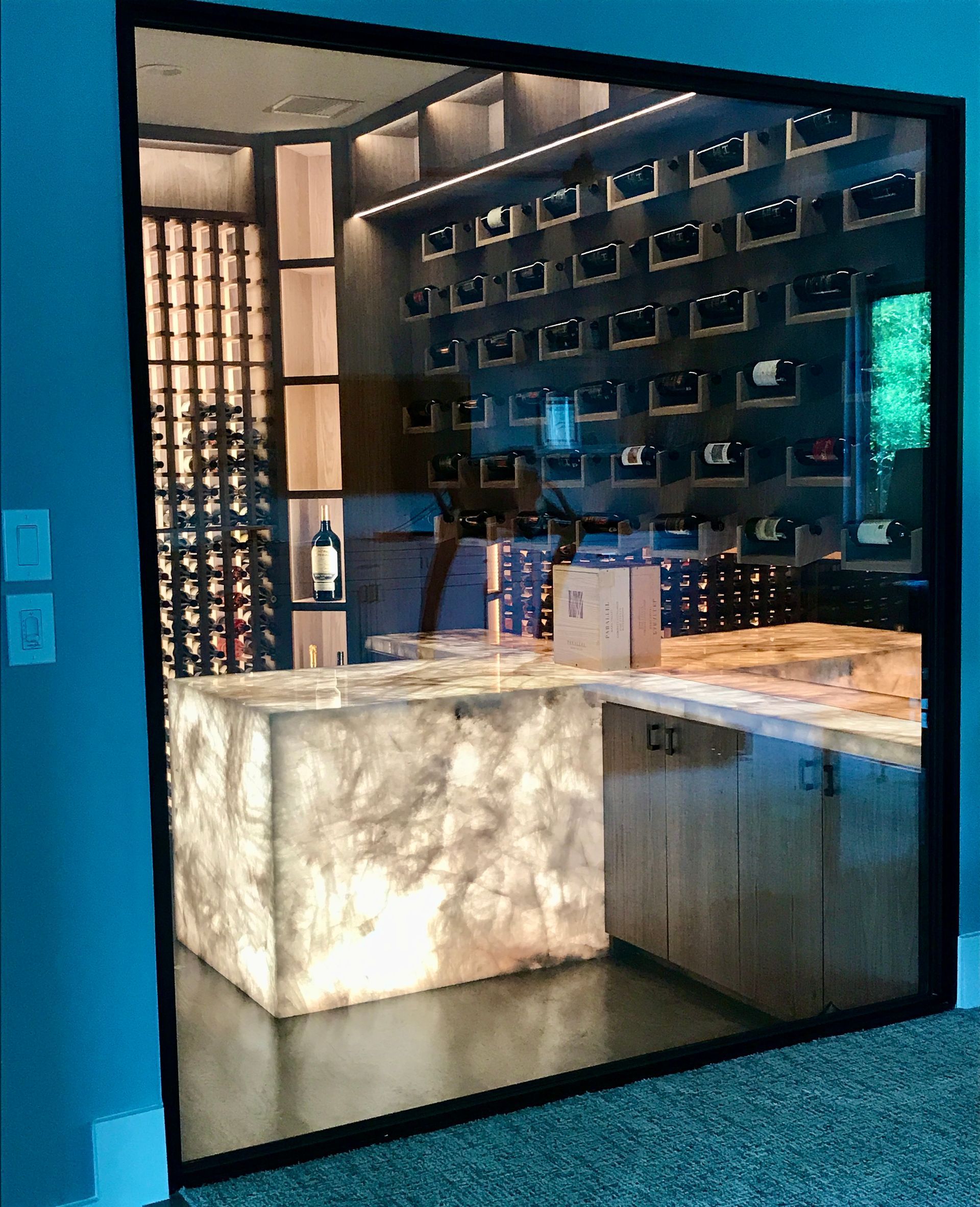 A large antique mirror shows a kitchen with a counter and bottles of wine.
