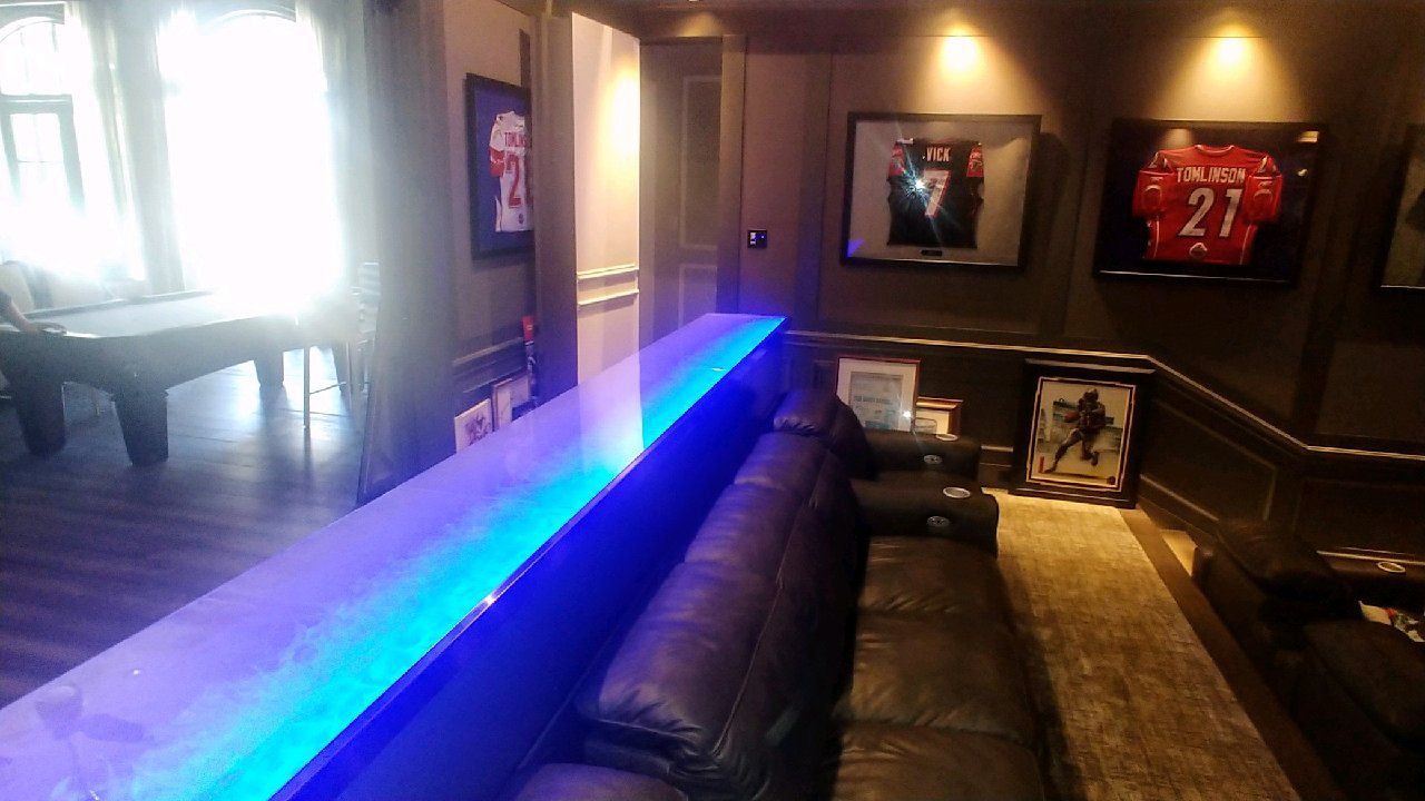 A living room with a couch and a pool table with blue glass counter top