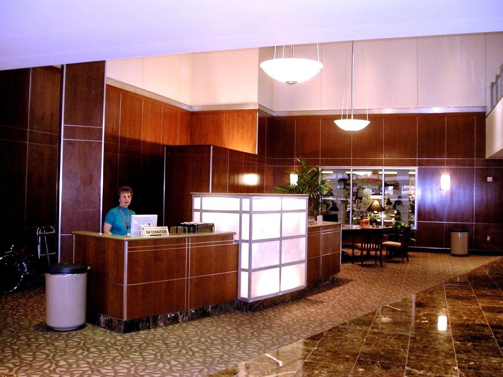 Hotel lobby with a reception desk, wood-paneled walls, and a glowing frosted glass divider