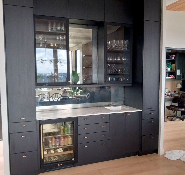 Black built-in bar with glass-front upper cabinets, a mirrored backsplash, and a wine fridge.