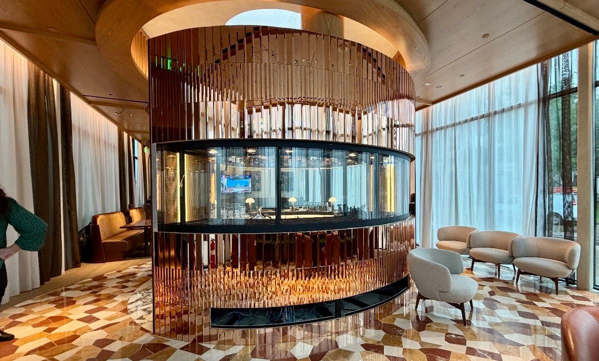 Modern lounge with a circular bar, curved seating, warm lighting, and floor-to-ceiling drapes Pink mirrors