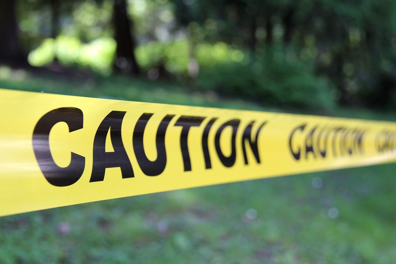 Police caution tape stretched across a forest.