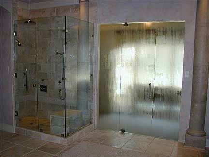 Two textured glass shower enclosures in a bathroom. One is clear, the other has condensation. Beige tile floor and walls.
