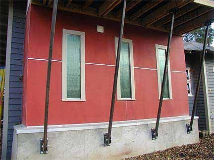 Red building exterior with three vertical textured glass windows and support beams.