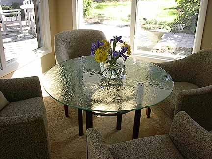 A glass table with a vase of flowers on it in a living room.