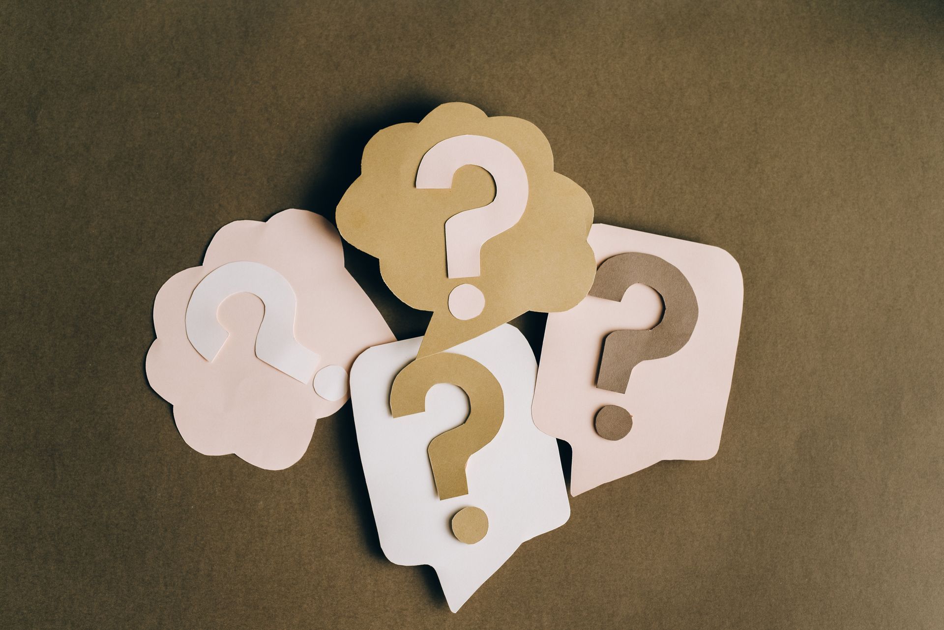 A bunch of question marks set against a brown background.