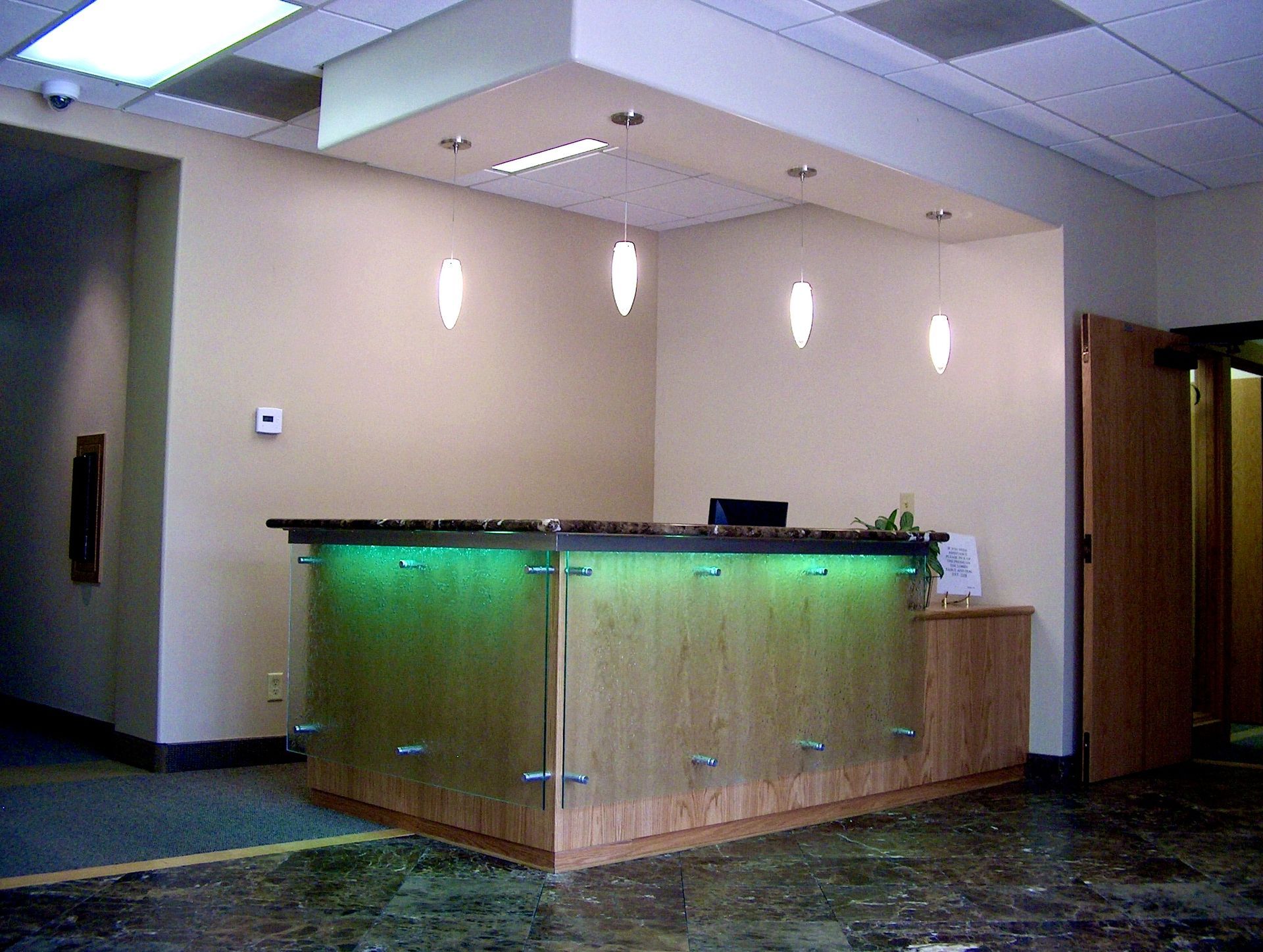 Modern office reception desk with green underlighting and beige walls in a lobby