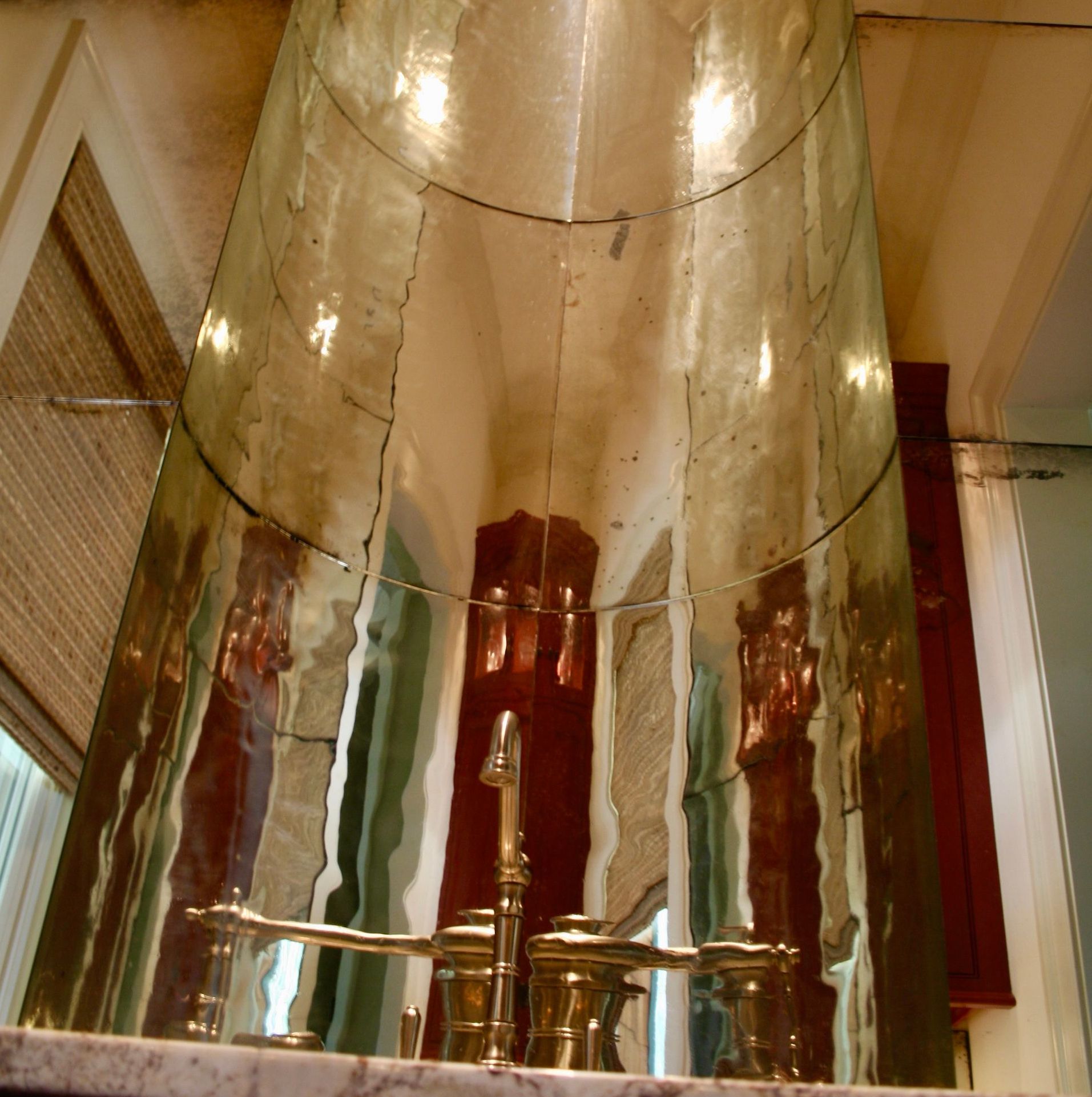 A bathroom sink with a large antique mirror behind it