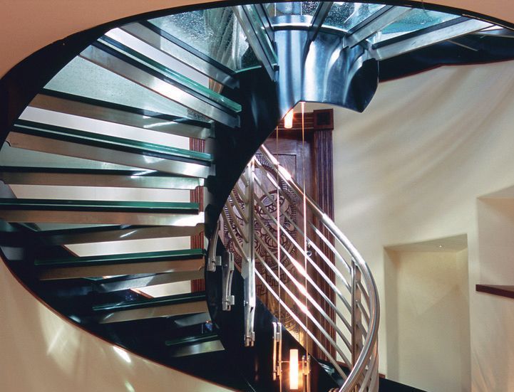 A spiral staircase with a stainless steel railing and glass steps