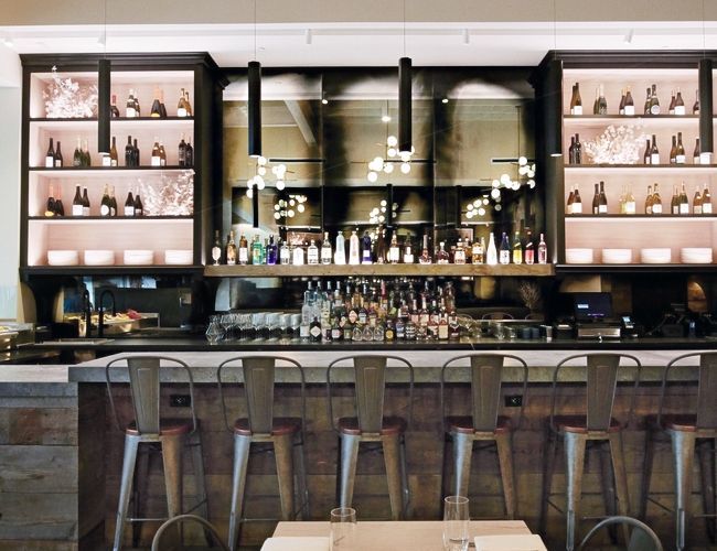 A restaurant with a bar and tables and stools with antique mirrors