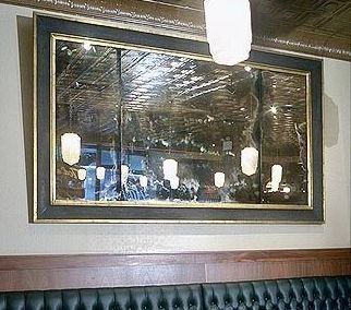 A large antique mirror is hanging on a wall in a restaurant.