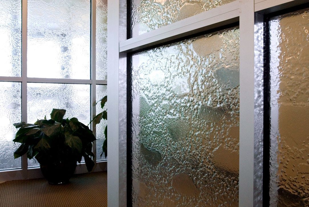 Frosted glass interior door beside a window, with a potted plant on a wooden sill.